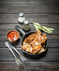 Fried bacon in a pan with tomato sauce and spices.
