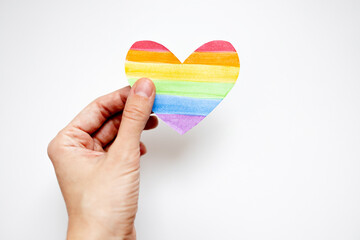 hand holding lgbt rainbow painted heart on white background.LGBT equal rights movement and gender...