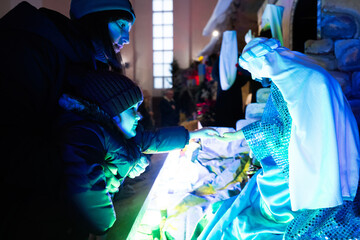 Mother with daughter looking at Christmas nativity crib scene in church.