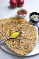 Indian traditional Hot Onion Paratha with tomato chutney. Indian onion stuffed Flatbread. also known as Pyaz ke parathe in Hindi. over a light background with copy space.