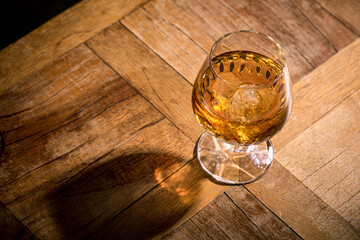 Glass of scotch whiskey and ice on old wooden table background with copy space