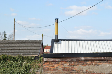 Metal Chimney on Corrugated Roof of Modern Industrial Building sen against Blue Sky  © eyepals