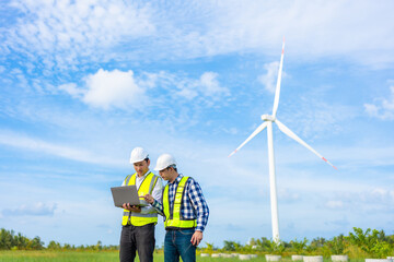 Male engineers or architects standing in a team meeting using a tablet Wear a helmet and a vest....