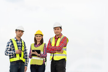 Photo of a team of 3 engineers or architects, man and woman smiling, standing together in strength and unity. Wear uniforms and helmets. Cool and smart, ready to work on industrial structures.