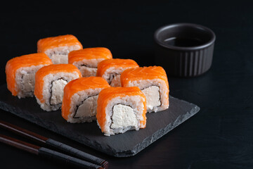 Sushi rolls closeup. Japanese food in restaurant. Philadelphia roll sushi on black slate background
