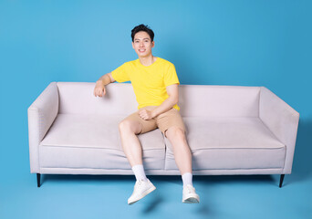 Image of young Asian man sitting on sofa