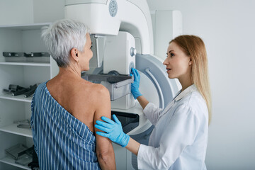 Fototapeta Senior woman having mammography scan at hospital with medical technician. Mammography procedure, breast cancer prevention obraz