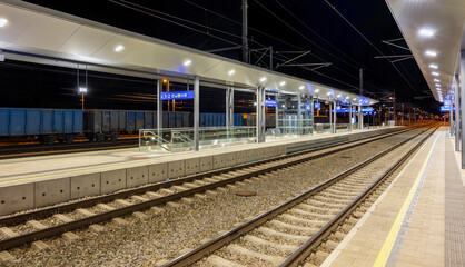  illuminated empty rail platforms of the station Tulln at the Danube at night, Austria