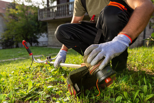 Close up of man hands on grass trimmer checking if machine is working properly