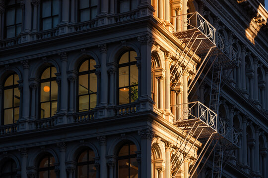 Last sun rays on Soho loft buildings with facade ornamentation and fire escape. Soho Cast Iron Building Historic District along lower Broadway, Lower Manhattan, New York City