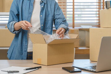 small business owner packing product order into parcel box at home office. online internet retail.