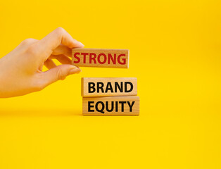 Strong Brand Equity symbol. Concept words Strong Brand Equity on wooden blocks. Businessman hand. Beautiful yellow background. Business and Strong Brand Equity concept. Copy space