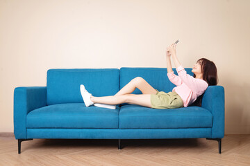 Fototapeta na wymiar Image of young Asian woman sitting on sofa