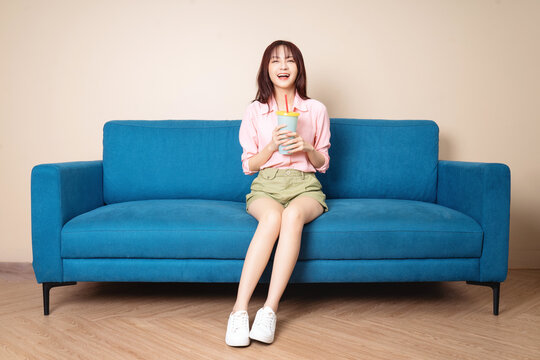 Image of young Asian woman sitting on sofa