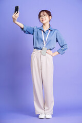 Photo of young Asian businesswoman holding smartphone on background