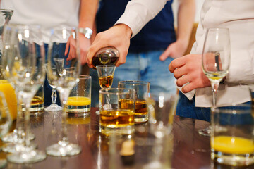 without faces. a man pours cognac in a stack. 