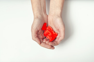 Female hands hold many small red hearts in their palms. White background.