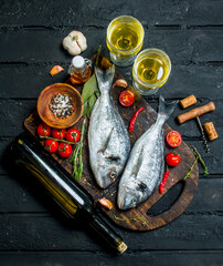 Raw sea fish dorado with glasses of white wine.