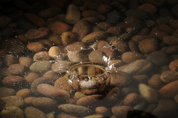 A pebble dropping into a shallow stony pool.