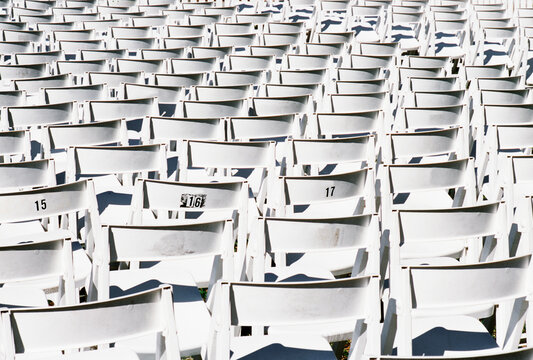 Rear view of rows of white plastic chairs.