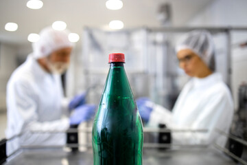 Water bottling plant and production line workers in background working in food and drink industry.