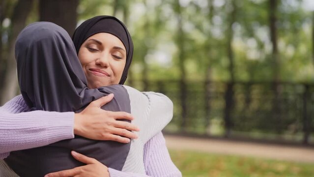 Happy muslim woman meeting and hugging best friend outdoor, close relationship