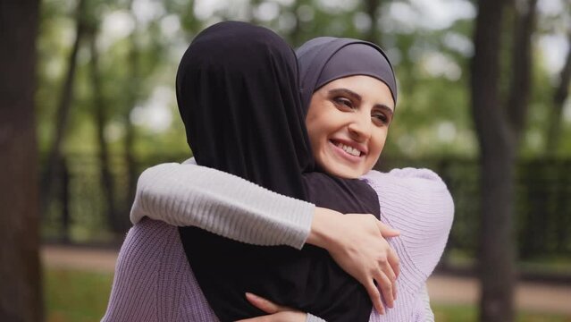 Smiling arab woman in hijab hugging best friend in park, long-awaited meeting
