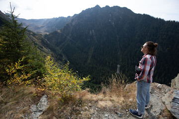 Fototapeta premium casual guy with tied hair and dark glasses looking at the mountains on a sunny day. view from behind. sunny mountains panorama