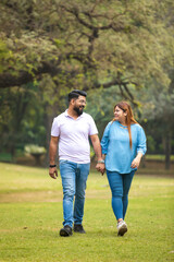 Fototapeta premium young indian couple holding hand each other and walking in park.
