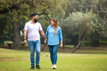 Fototapeta premium young indian couple holding hand each other and walking in park.