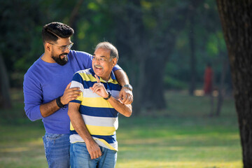 Old indian father with his young son spending time at park.