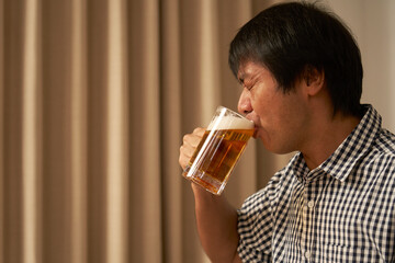 家でビールを飲む中年男性