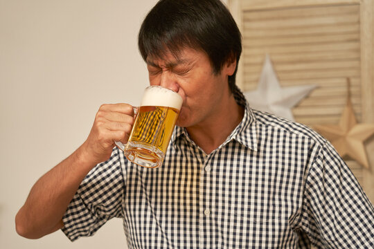 家でビールを飲む中年男性