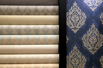 Rolls of vinyl wallpaper in building store. Wallpaper with floral, geometric pattern for wall, repair materials.