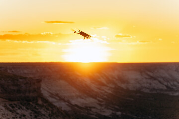 Fototapeta na wymiar Drone in epic flight against dramatic golden sunset in remote location by the desert cliffs
