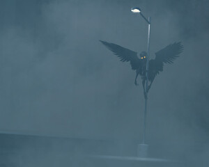 3d illustration of the Mothman or similar winged cryptid  clinging to a street lamp in a parking lot or car park on a foggy night