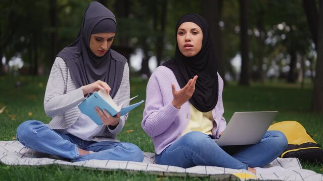 Multicultural muslim students studying in park, preparing for exams on campus