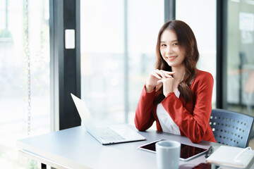 Portrait of a woman business owner showing a happy smiling face as he has successfully invested her business using computers and financial budget documents at work