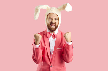 Positively excited man in hat with rabbit ears rejoices in his luck isolated on pink background....
