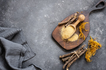 Licorice root, licorice fiber and powder in spoon on rustic background ( glycyrrhiza glabra )