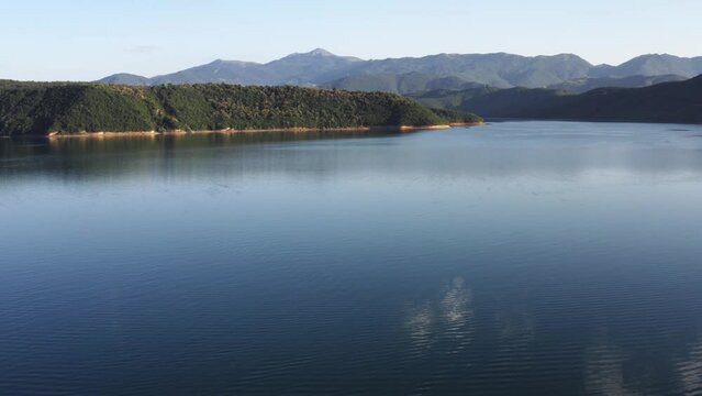 Flying low over a serene lake surrounded by mountains in Northern Macedonia