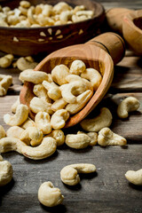 Cashews in a bowl with a wooden scoop.