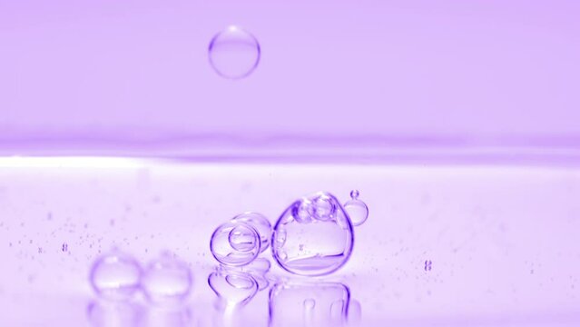 Macro shot of purple transparent bubbles sink to the liquid surface on purple background | Abstract skincare cosmetics with niacinamide formulation concept
