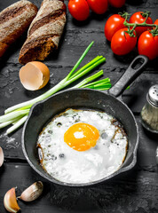 Fried egg in a pan with bread and tomatoes.