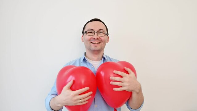 Young man in glasses holds Love balloons on white background. Valentines day,anniversary,birthday concept	
