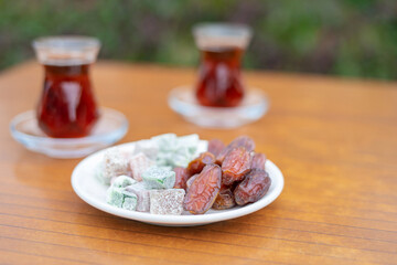 Dry Dates in a bowl and tea in armudu glass. Ramadan kareem.  Outdoor  background.