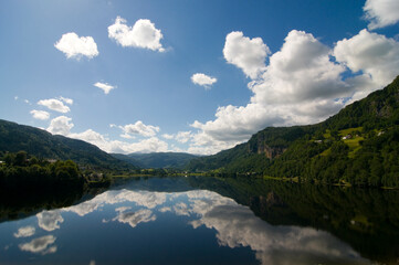 Obraz premium Mountains, clouds and sky reflected in the lake at Norheimsund on the Hardanger fjord, Western Norway.