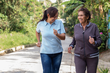 Cheerful elderly mother and daughter jogging outdoors in a morning exercise. Healthy living concept