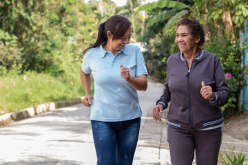 Obraz premium Cheerful elderly mother and daughter jogging outdoors in a morning exercise. Healthy living concept