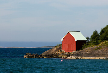 single red boathouse with sun and sea, near ulsteinvik, Western Norway.